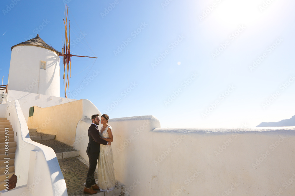 bride and groom posing near a white windmill