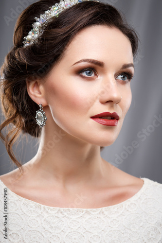 Elegant young woman with perfect makeup and hair style in a white dress. Beauty fashion portrait with accessories