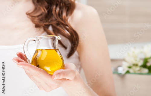 Unrecognizable woman holding glass jug with olive oil photo