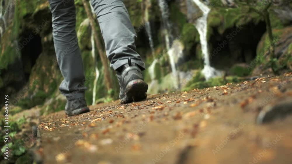 Close up of feet walking on wooden bridge toward waterfall in slow motion Close up of feet walking on wooden bridge toward waterfall in slow motion