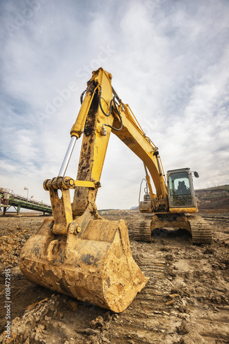 One side of mining dredge photographed from a ground with wide angle lens. Dramatic cloudy sky in background.