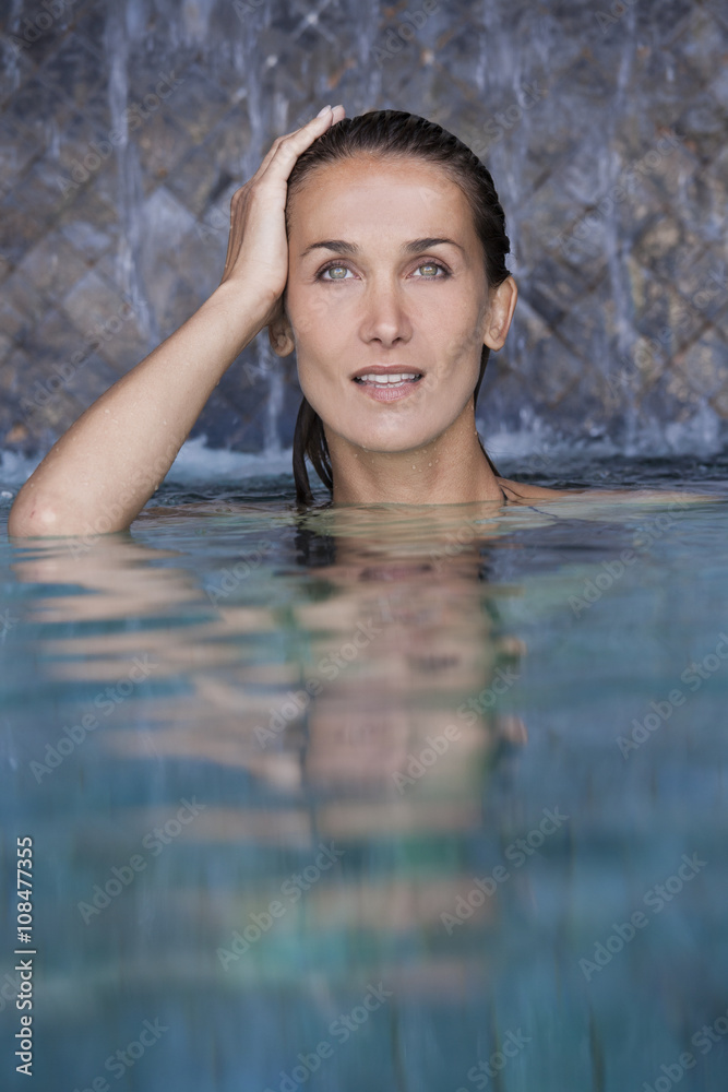 belle femme sous des chutes d'eau dans une piscine