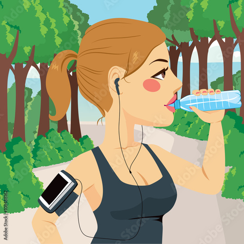 Beautiful young runner woman drinking bottled mineral water on park