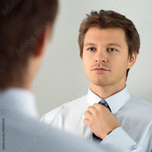 Valokuva Handsome businessman preparing to official event, straighten tie