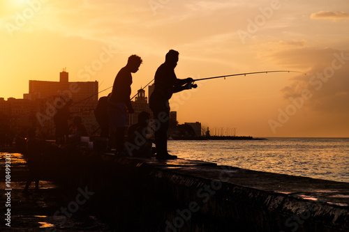 Sunset in Havana with the silhouette of group of fishermen