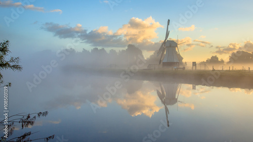 Reflection of White wooden windmill in river