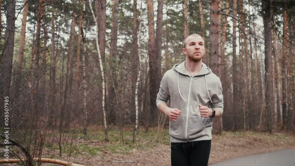 Man running in forest woods training and look at smart watches. Man running in forest woods training and look at smart watches.