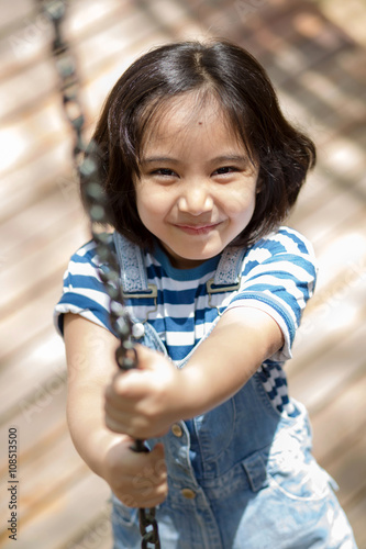Cute children. Asian girl climbing in a chain playground structure at adventure park
