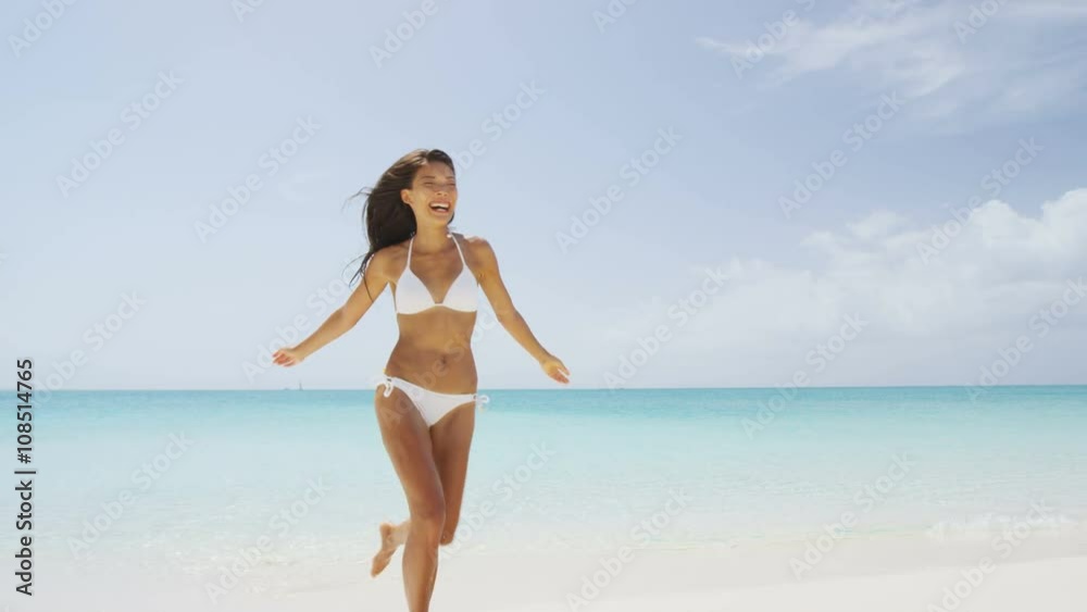 Beach bikini woman carefree running in freedom fun. Joyful happy Asian girl relaxing showing joy and happiness in slim body for weight loss diet concept on perfect white sand. Throwing beach hat. Beach bikini woman carefree running in freedom fun. Joyful happy Asian girl relaxing showing joy and happiness in slim body for weight loss diet concept on perfect white sand. Throwing beach hat.