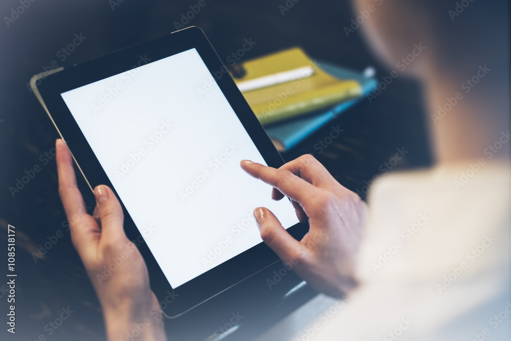 Girl pointing finger to an blank display of the tablet with a blue color in a homelike atmosphere on warm bokeh background lighting color, female hands using computer in cafe with reflection and glare Girl pointing finger to an blank display of the tablet with a blue color in a homelike atmosphere on warm bokeh background lighting color, female hands using computer in cafe with reflection and glare