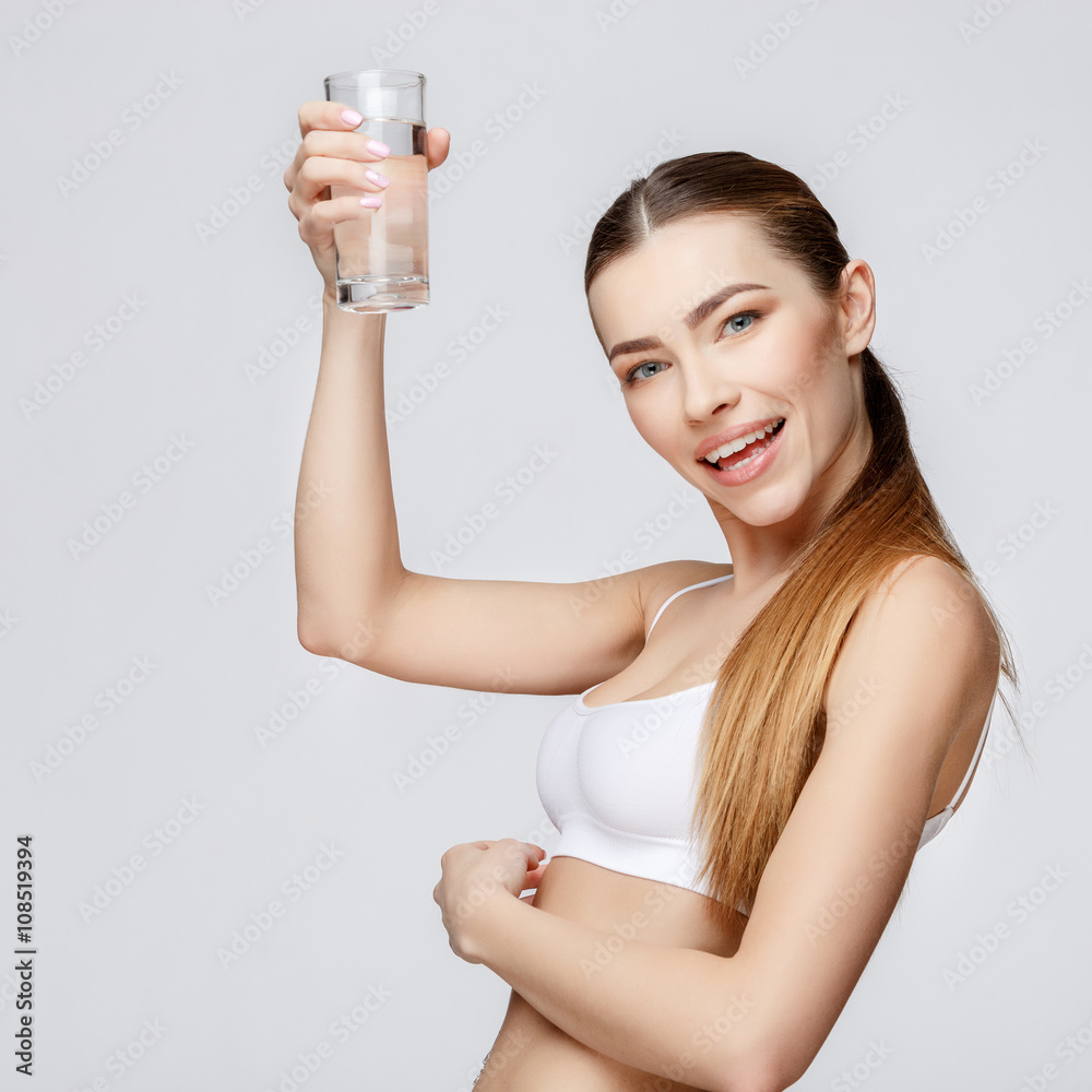 sporty woman over gray background holding glass of water sporty woman over gray background holding glass of water