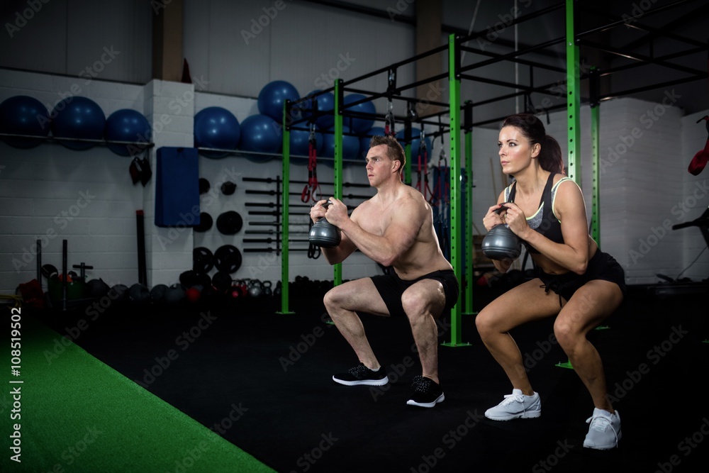 Man and woman exercising with kettlebell Man and woman exercising with kettlebell