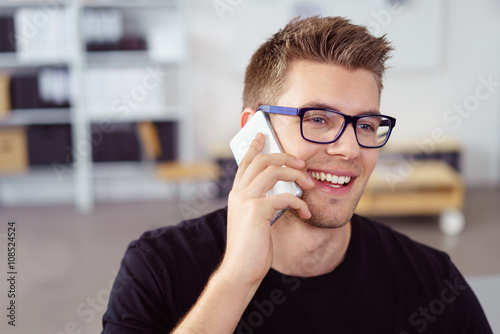lächelnder junger mann telefoniert mit seinem handy
