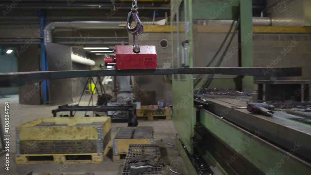 The red magnetic tool carrying a big metal. The curved black metal is being carried by the magnet in a chain The red magnetic tool carrying a big metal. The curved black metal is being carried by the magnet in a chain