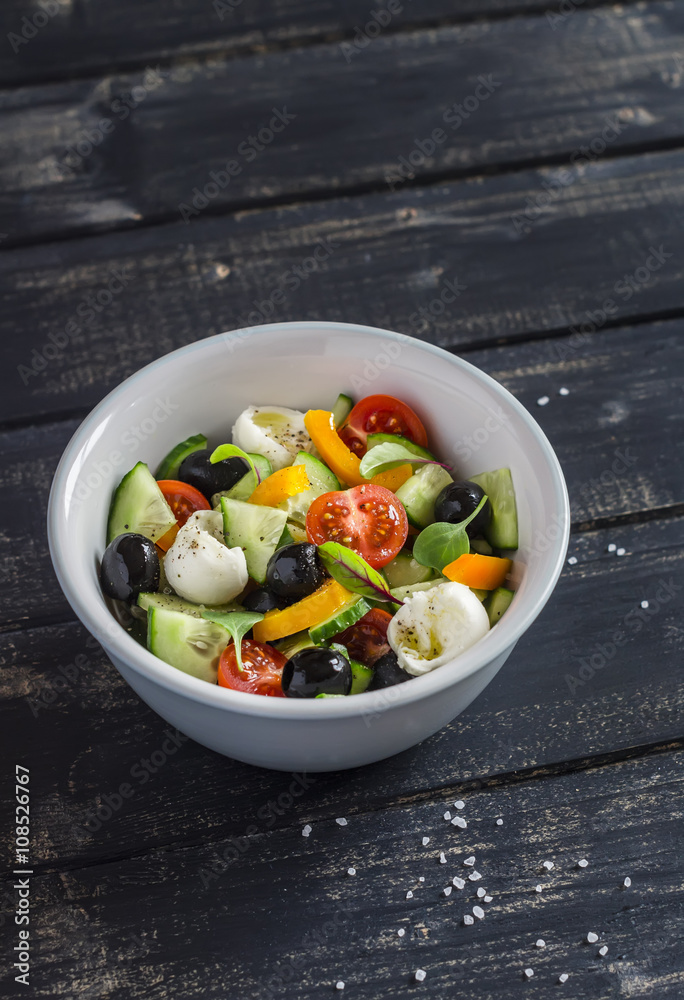 Fresh salad with tomatoes, cucumbers, peppers, olives and cheese in a ceramic bowl on dark wooden background Fresh salad with tomatoes, cucumbers, peppers, olives and cheese in a ceramic bowl on dark wooden background