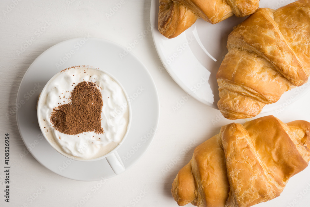 Croissants with cup of coffee on wooden background