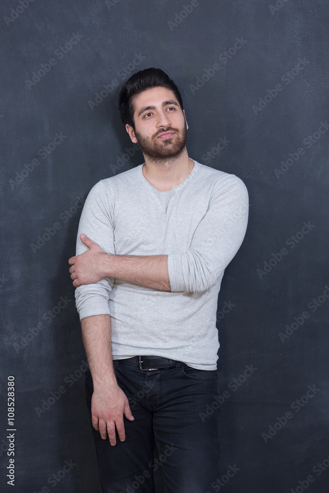 a young man with a beard on a chalkboard background with the emo