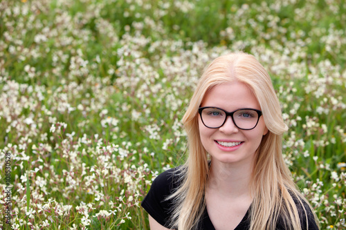 Blonde girl with glasses surrounded by flowers