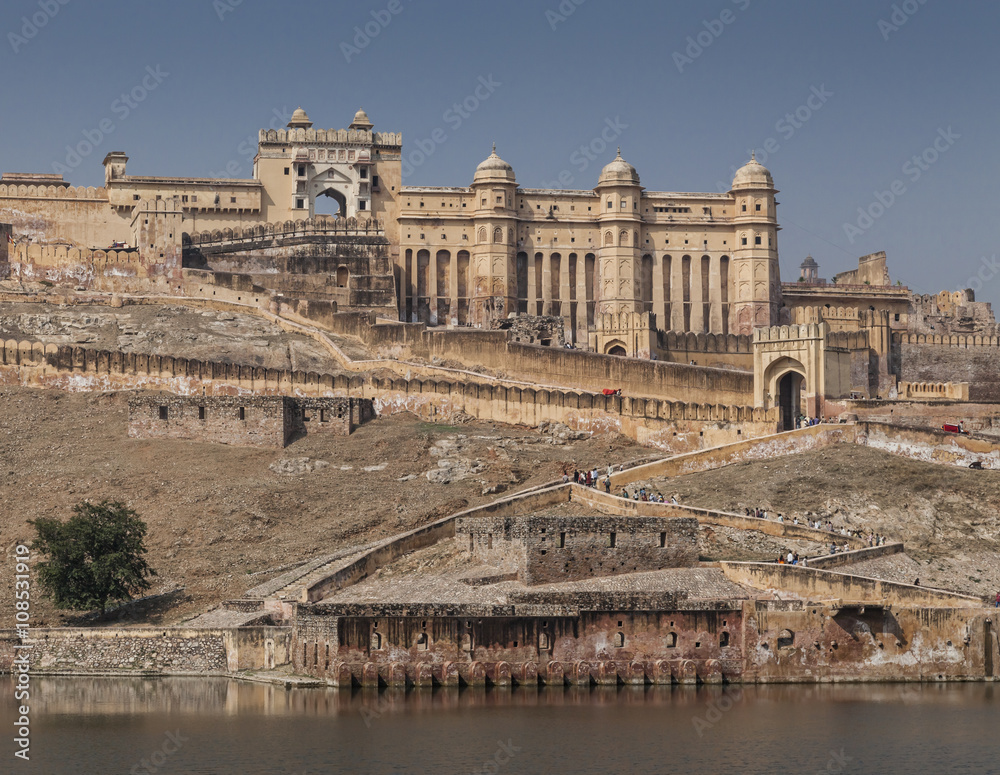 The ancient Amber Fort, Jaipur showing the lake in the foreground, against a blue sky