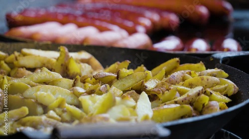 Potato fries and hotdogs on the pan. Cooked on a different pan for sale on the street side photo