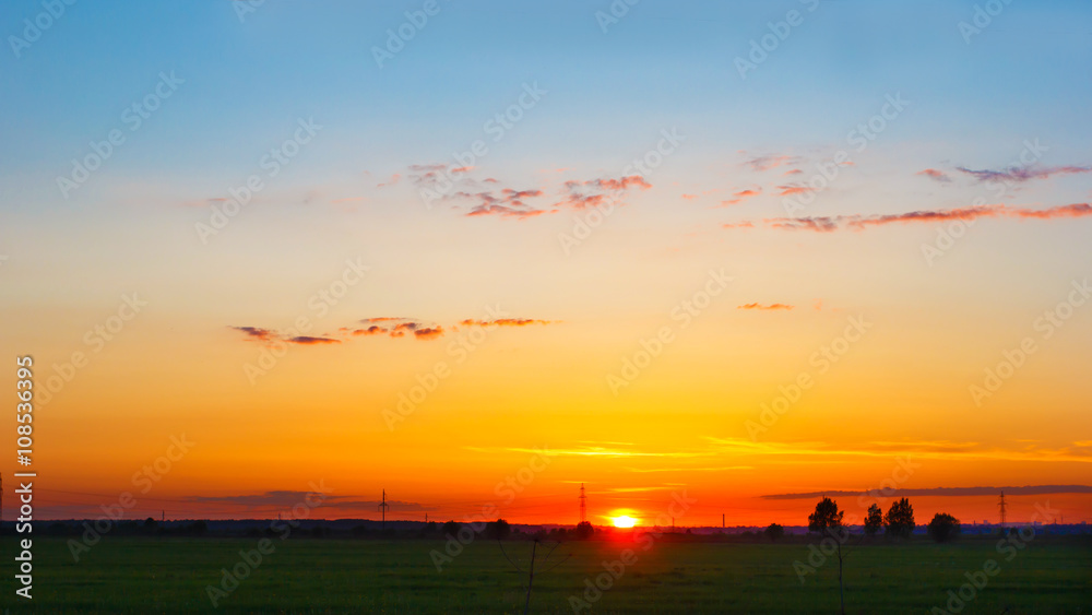 Panorama with sunset over the horizon on a summer evening. Landscape with the sun setting over the horizon. Grand fantastic view.