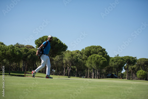 golf player walking and carrying bag