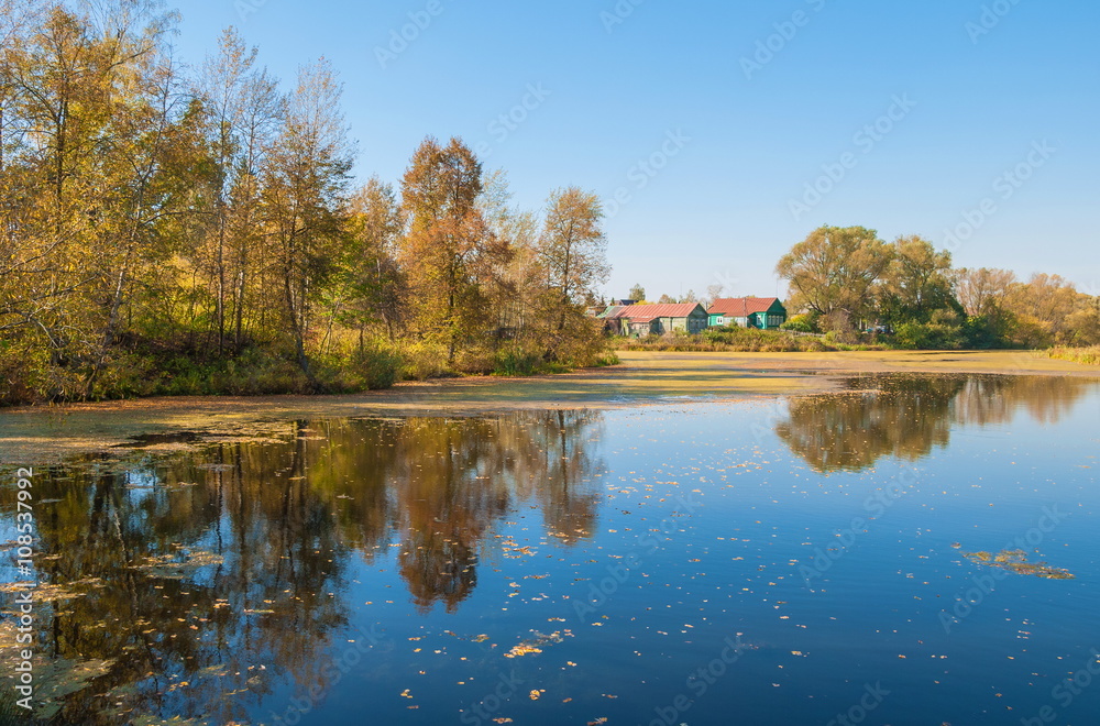 Autumn landscape with a small village on the river bank