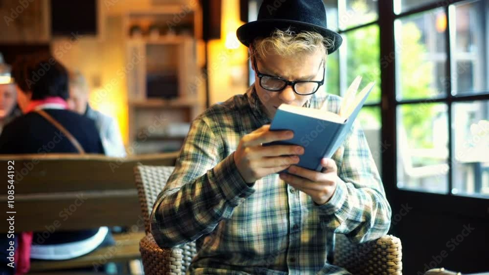 Boy reading a book in the cafe and browsing internet on tablet
Boy reading a book in the cafe and browsing internet on tablet