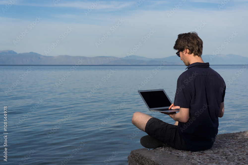 Young man working near the sea