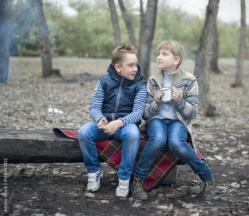 two kids sitting on the wooden bench in the park cookout the mar two kids sitting on the wooden bench in the park cookout the mar