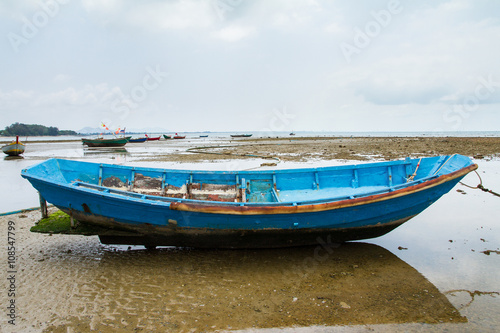 An old fishing boat moored beached on the beach at low tide.