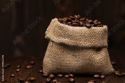 Coffee beans in a title bag, on dark wooden surface