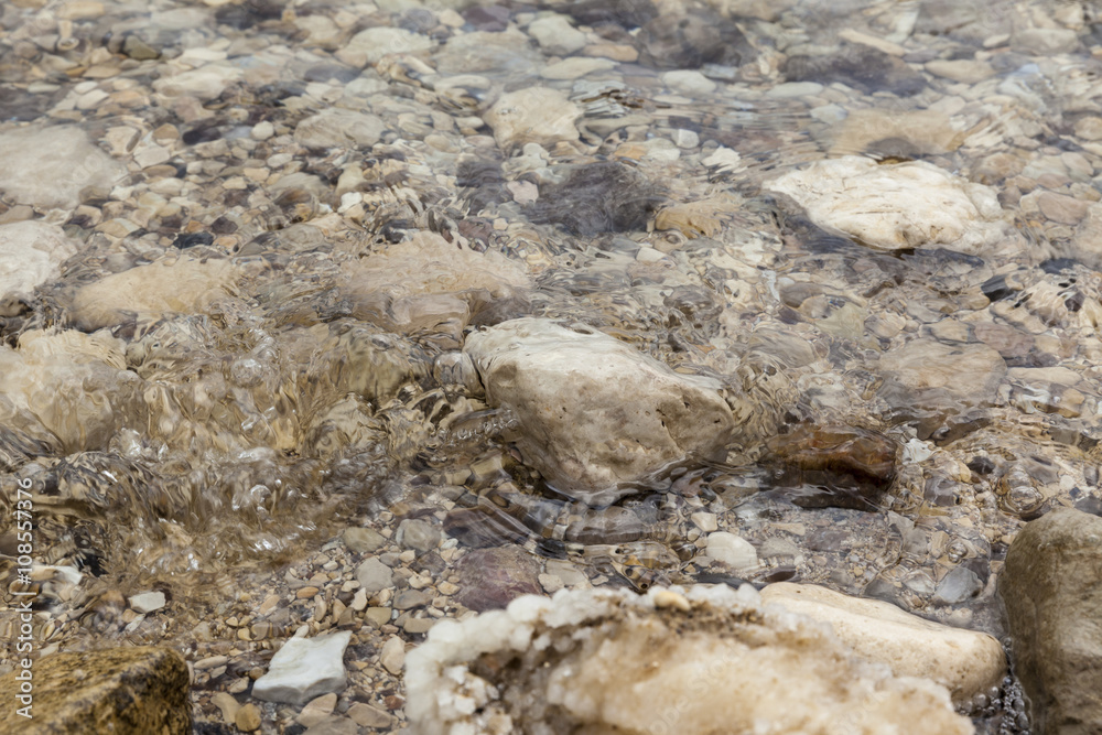 Fototapeta premium Wave washing a boulder at water edge