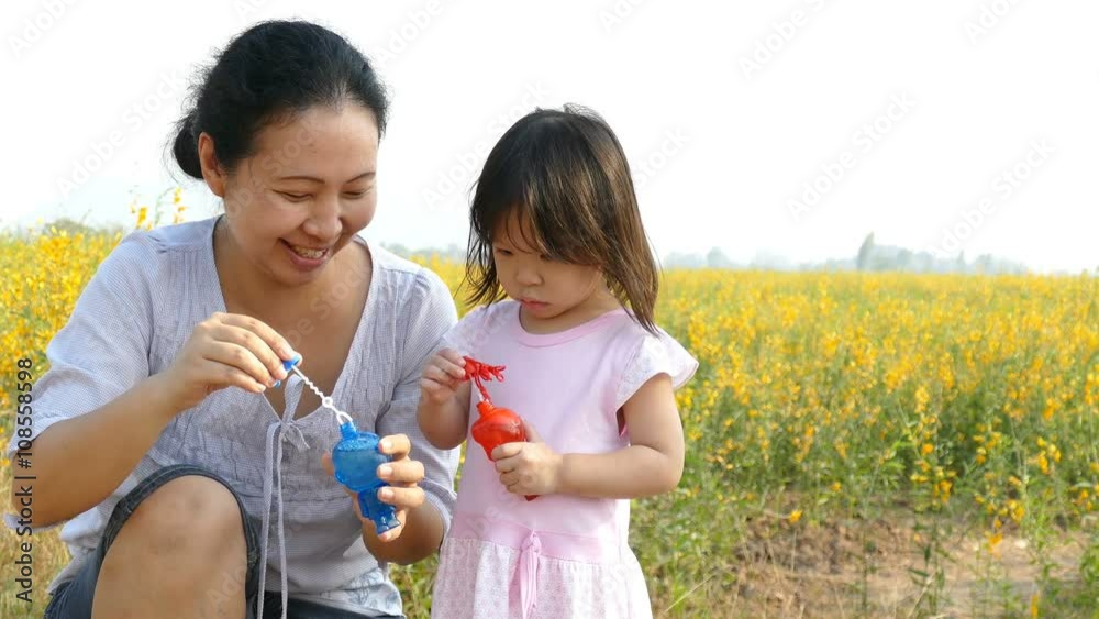 Mother and cute Daughter blowing bubbles in flower field Mother and cute Daughter blowing bubbles in flower field