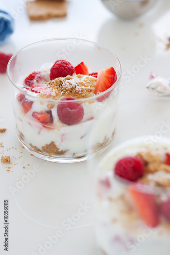 Homemade healthy dessert in a glass with yogurt, fresh fruits and cookies for breakfast, closeup.