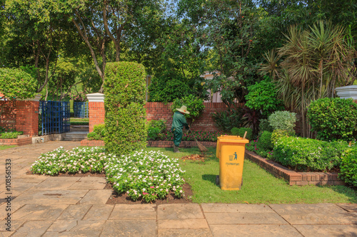 Asian worker man cleaning garden with tool sweep