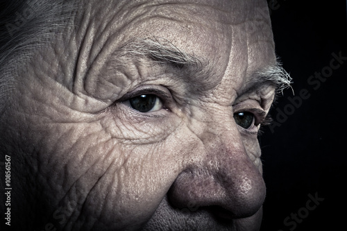 Portrait of elderly woman on dark background. Toned