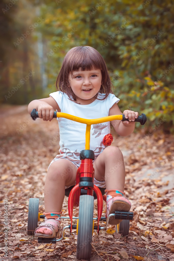 Adorable girl riding a bike on beautiful autumn day. childhood, leisure, friendship and people concept. walks in the woods on a sunny autumn day. Children playing outdoors. Happy family. series Adorable girl riding a bike on beautiful autumn day. childhood, leisure, friendship and people concept. walks in the woods on a sunny autumn day. Children playing outdoors. Happy family. series
