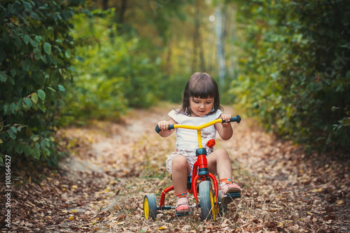 Adorable girl riding a bike on beautiful autumn day. childhood, leisure, friendship and people concept. walks in the woods on a sunny autumn day. Children playing outdoors. Happy family. series