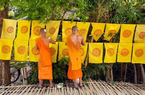 Buddhist monks decorated by flags with religious symbols all area outside monastery
