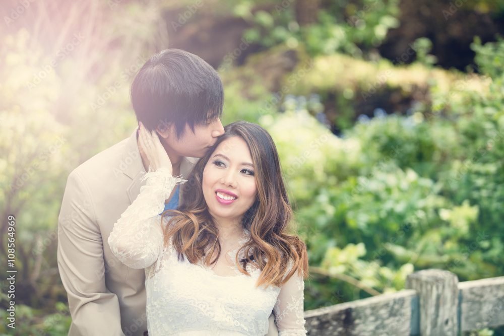 Expecting mom receiving kiss from her husband while outdoors