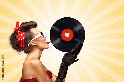 Tastes like music / Vintage photo of glamorous pinup girl, red ribbon in her hair and sunglasses, touching retro vinyl with her tongue on colorful abstract cartoon style background.