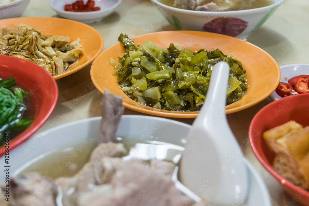 Chinese local foods on table, bak kut teh, vegetables, tofu and chili side dishes, selective focus on vegetable Chinese local foods on table, bak kut teh, vegetables, tofu and chili side dishes, selective focus on vegetable