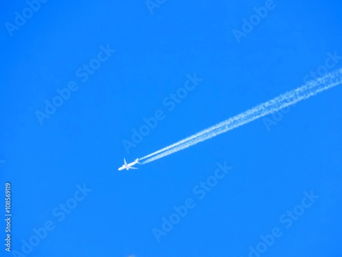 Airplane with chemtrails on blue sky