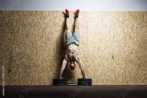 Valokuva Bodybuilder doing handstand at the wall in the gym