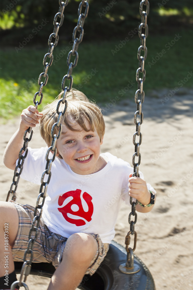 portrait of a cheerful boy sitting on tire swing. portrait of a cheerful boy sitting on tire swing.