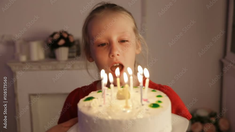 Young girl is blowing out candles on cake.Girl blows out the candles on birthday cake with lots of candles.