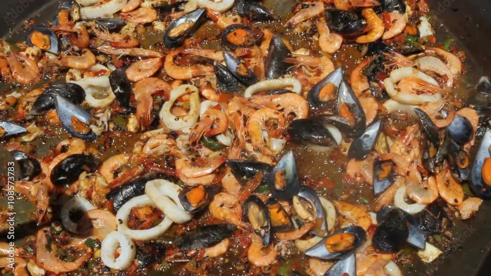 Sofriendo los ingredientes basicos para la preparacion de una paella de marisco al aire libre