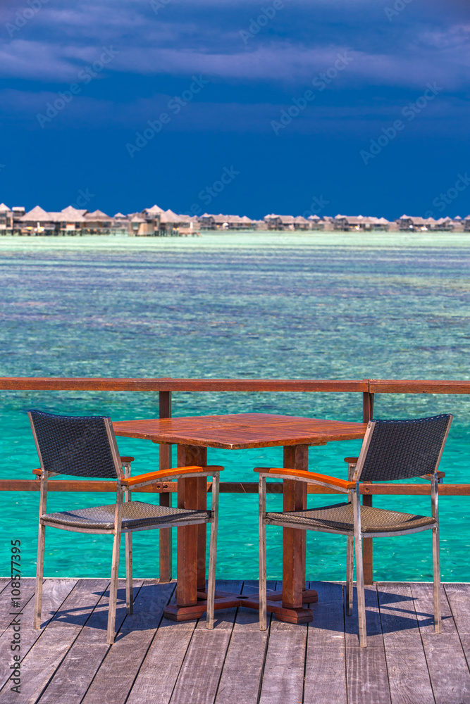 Chairs and table on tropical island with sandy beach and tourquise clear water, Maldives