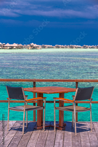 Chairs and table on tropical island with sandy beach and tourquise clear water  Maldives